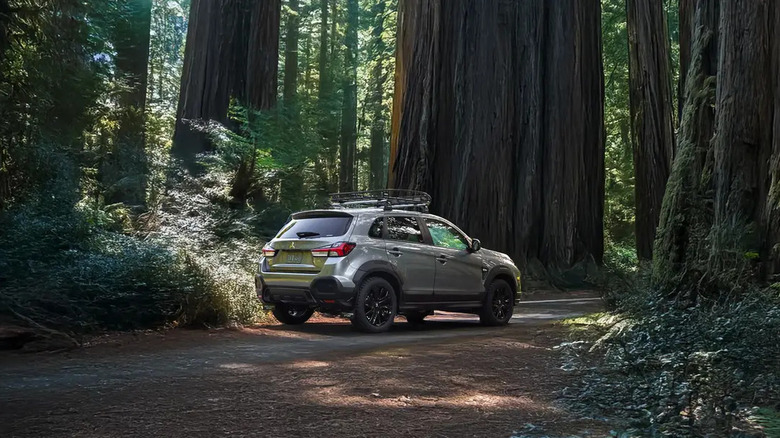 A 2026 Mitsubishi Outlander Sport crossover SUV standing in a clearing in a forest, right three-quarter view shown.