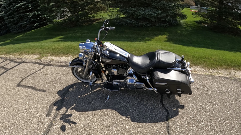 A silvery and black Harley Davidson Road King Classic from the early 2000s parked at the side of an asphalt road.