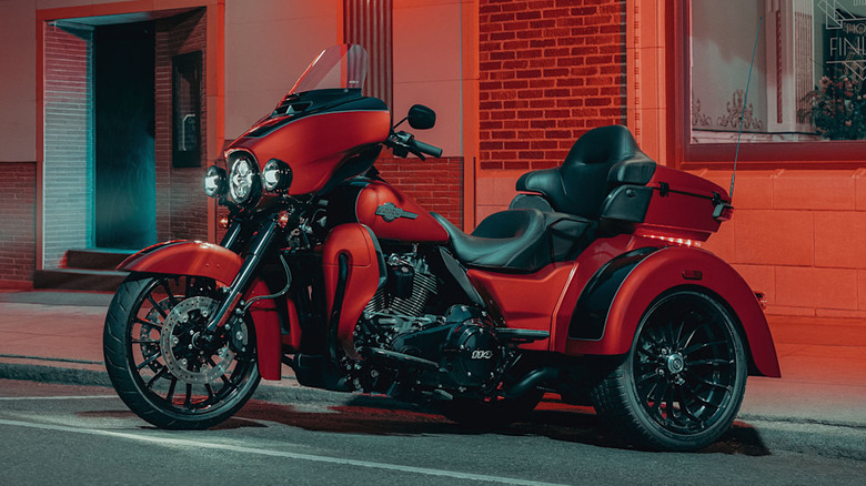A red Harley Davidson Tri-Glide Ultra for the 2025 model year parked in neon lighting outside a building.