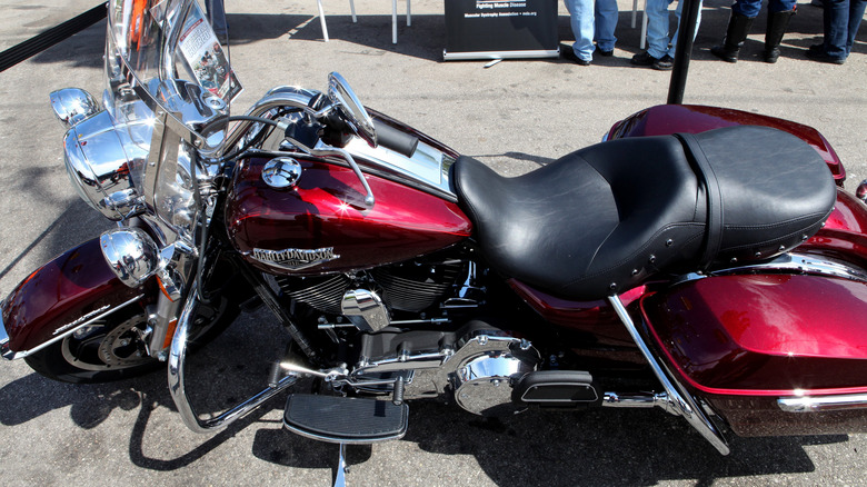 A red Harley-Davidson Road King motorcycle, with chrome accents, parked on its kickstand outside.