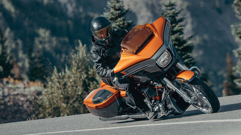 A rider in full gear taking a corner aggressively on a 2026 Harley CVO Street Glide, finished in orange.