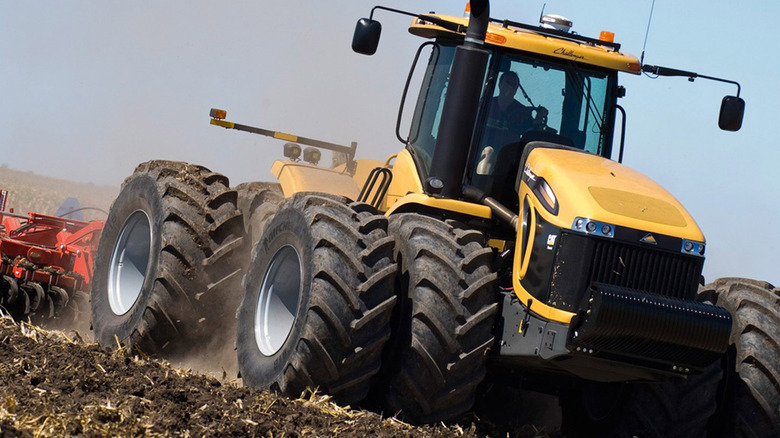 A yellow Challenger tractor plowing a field