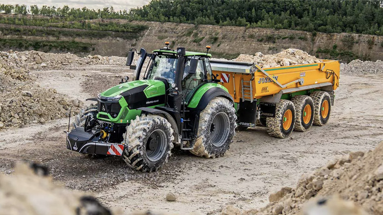 A green tractor pulling a load of rocks at a construction site
