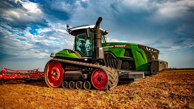 A green Fendt 1100 MT riding on a farm