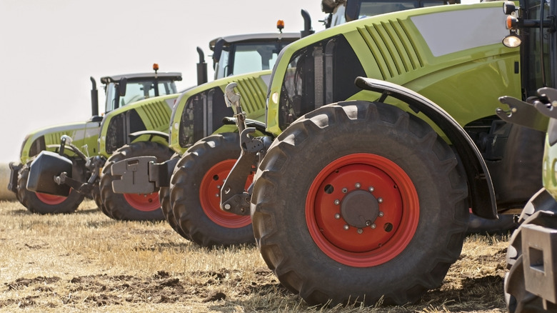 A couple standing next to a massive white tractor