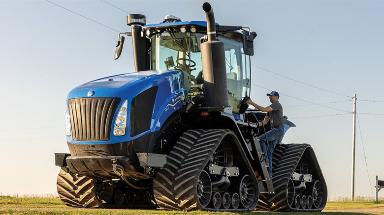 A blue New Holland T9 tractor driving on a farm
