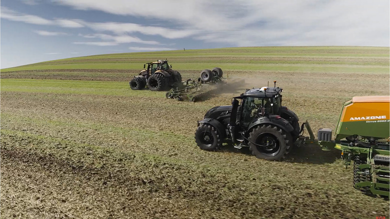Two Valtra tractors driving on a farm