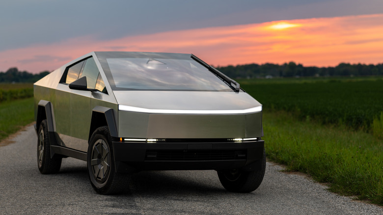 A Tesla Cybertruck on a gravel road backing a fading sunset