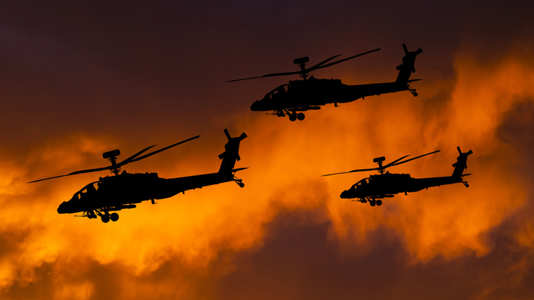 Three attack helicopters flying at sunset
