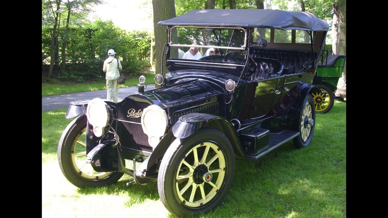 Black 1916 Packard Twin Six Model 1-35 Touring Sedan seen from front left parked at outdoor show
