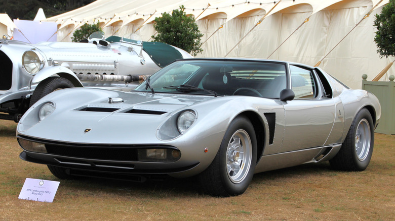 Silver Lamborghini Miura SV/J supercar seen from front left on display at an outdoor show