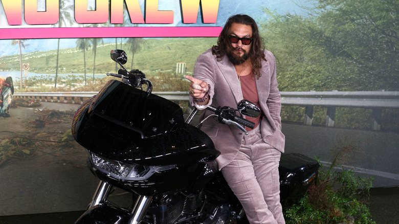 Jason Momoa posing with a motorcycle at a movie event