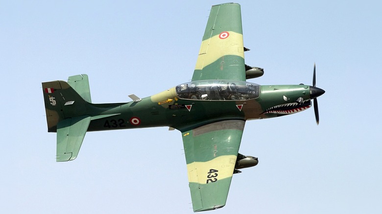 A Peruvian Air Force - Embraer T-27 Tucano with green camo paint flying over blue skies