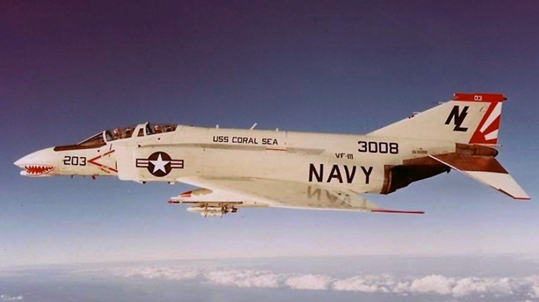 A U.S. Navy McDonnell F-4B Phantom II operating from the USS Coral Sea in flight over clouds covering the water