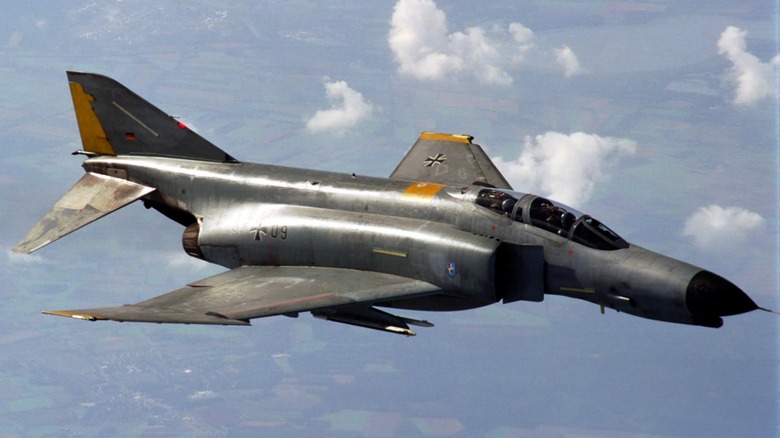 A McDonnell Douglas F4 Phantom II flying over sparsely cloudy skies.