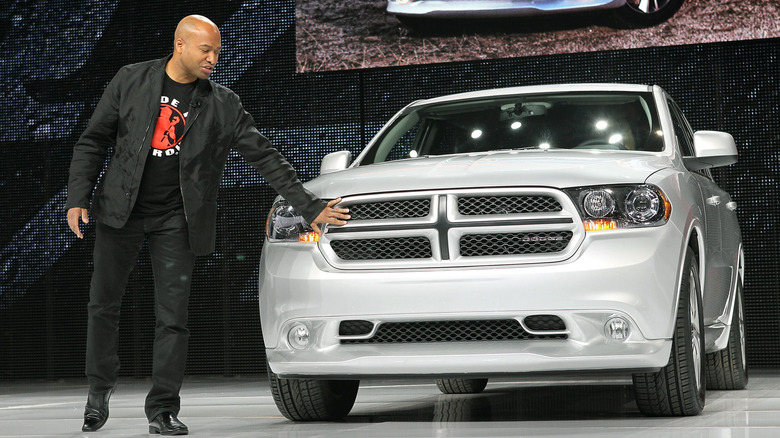Ralph Gilles, the CEO of Dodge in 2011, standing next to a white 2011 Dodge Durango.