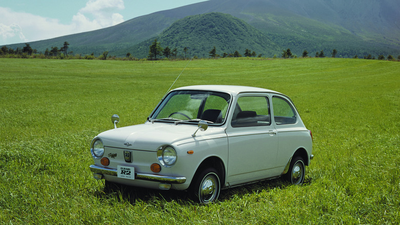 1969 Subaru R-2 parked on meadow with mountains in the background