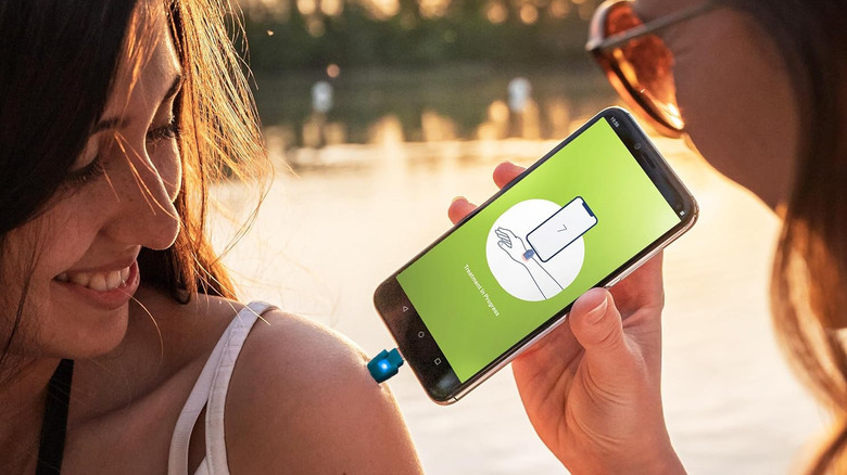 A woman applying heat to a girl's insect bite using the Heat It dongle.