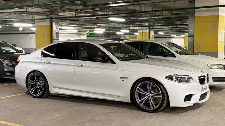 A white BMW F10 parked in a multistorey parking, facing towards the right.