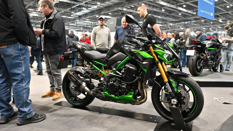 A black and Green Kawasaki Z900 SE Performance bike on display on an indoor stand at a trade show.