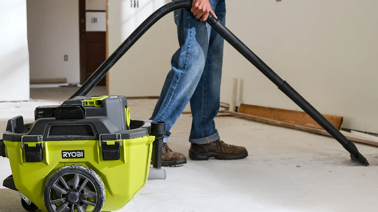 A person vacuuming a floor with a Ryobi shop vac.