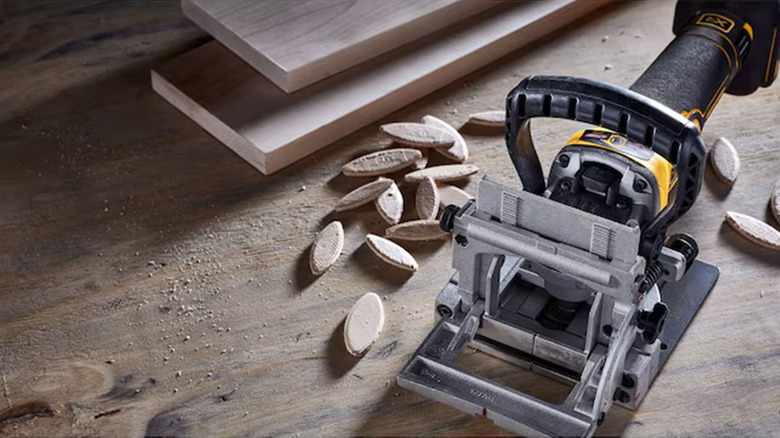 A DeWalt biscuit joiner on a wood floor with wood biscuits