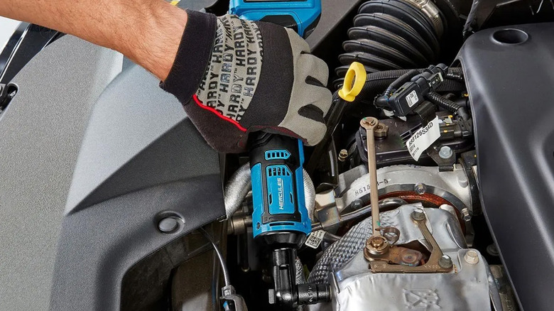 A mechanic using a Hercules cordless ratchet in a car's engine bay.