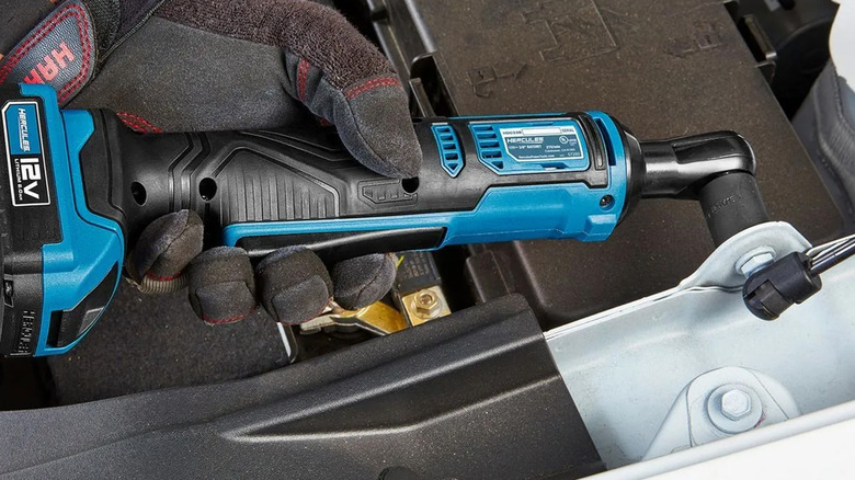 A mechanic using a Hercules ratchet on a car frame.