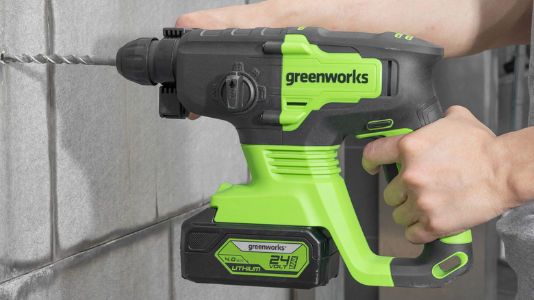 Person using Greenworks hammer drill on brick wall