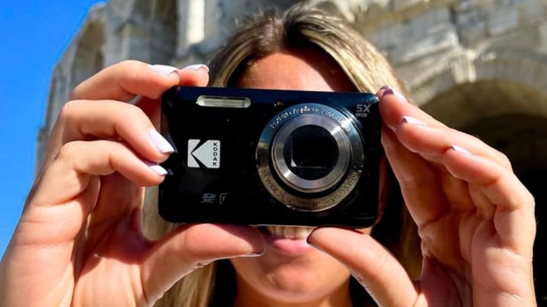 A person holding a digital camera up to their face