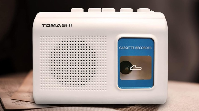 A Tomashi portable cassette player on a surface with papers underneath it