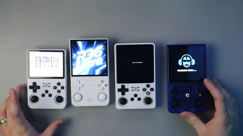 A group of handheld consoles inspired by '90s designs with a pair of hands showing them off
