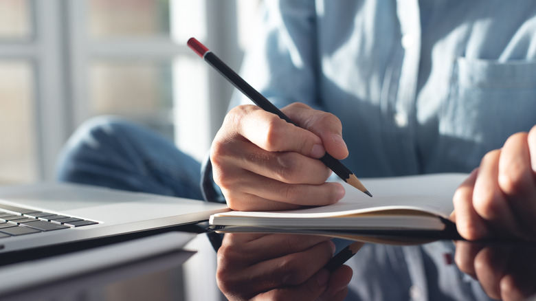 Worker at a desk with a latptop, pencil and paper