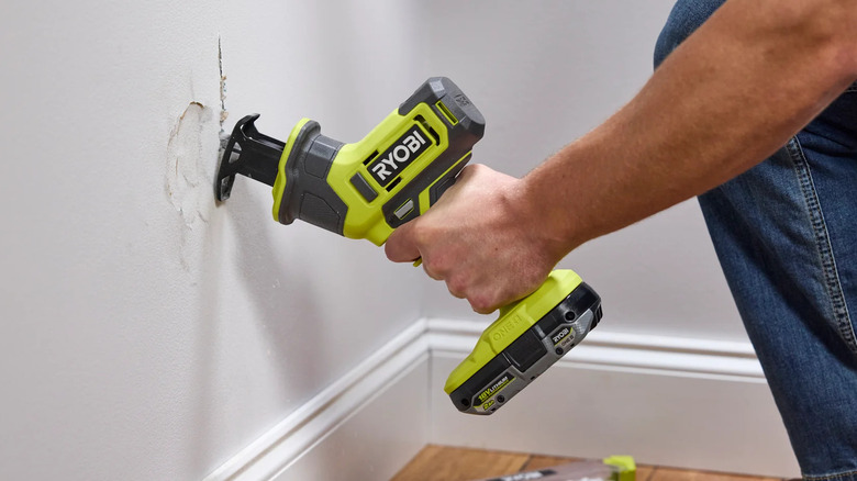 Ryobi one-handed reciprocating saw cutting through drywall