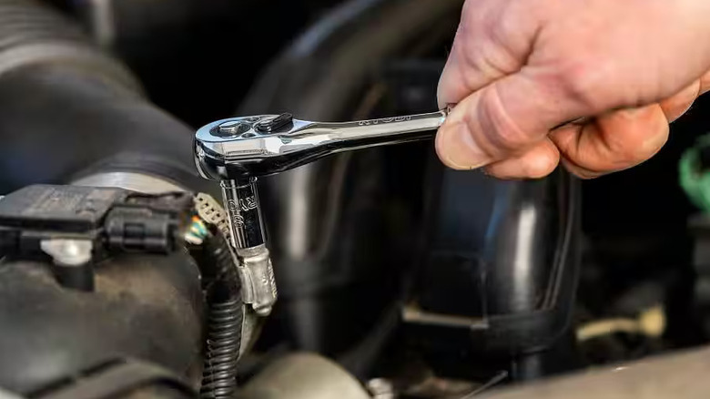 Closeup of a Ryobi ratchet loosening a bolt in an engine bay