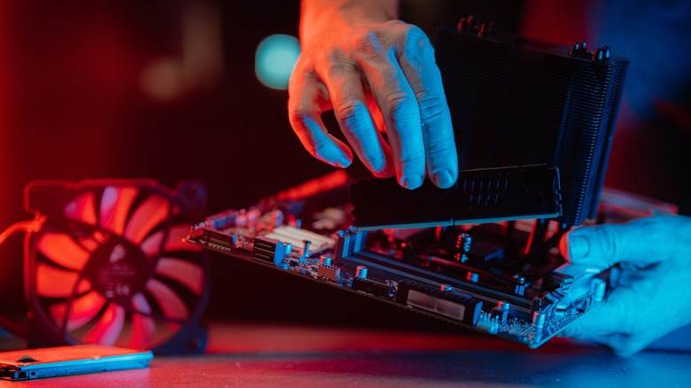 Hands assembling computer parts in red-blue light