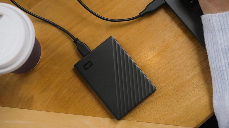 WD My Passport external hard drive on a tabletop surface, plugged into a laptop