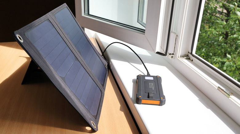 Two-panel solar device charging a small black box inside a home