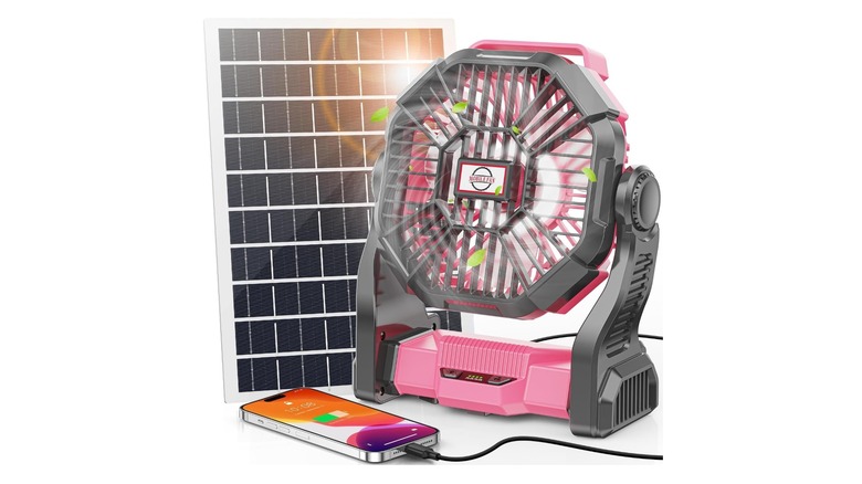 Pink fan next to a solar panel while charging a phone against a white background