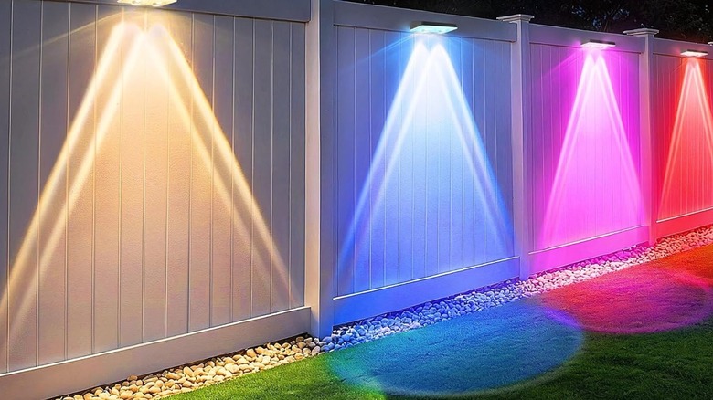 Colored downlights illuminating sections of a white fence