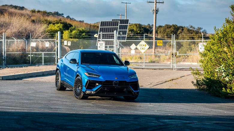 A chrome blue Lamborghini Urus exiting a restricted area