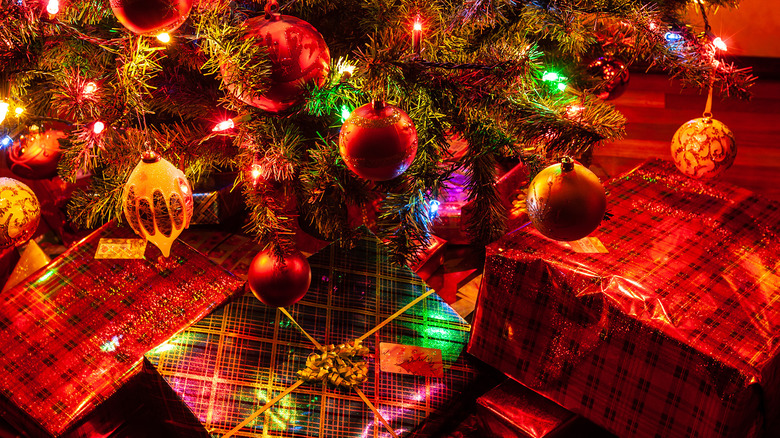 A pile of Christmas presents under a tree close up