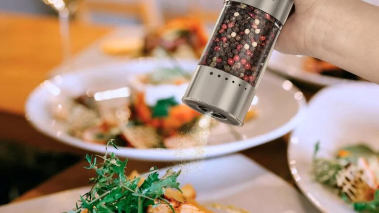 A pepper shaker depositing pepper on food