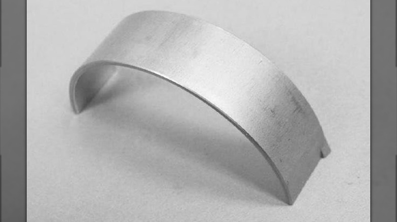 A piston oil cooler jet on a gray surface.