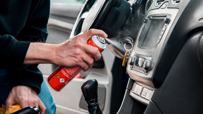 a person using an aerosol can in a car