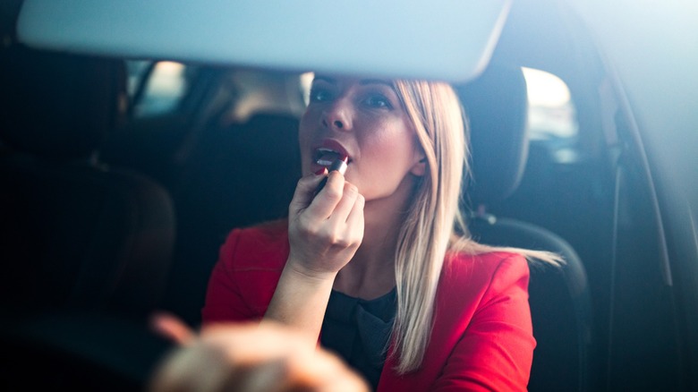 a person putting on lipstick in the car
