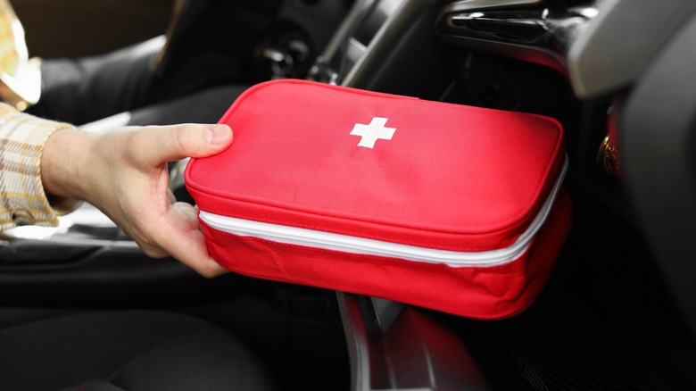 a medicine bag being taken from the glove compartment of a car