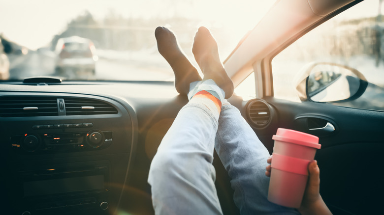 A woman with her feet on top of the car dashboard