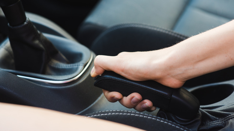 Female driver wrongly pulling the handbrake of a car