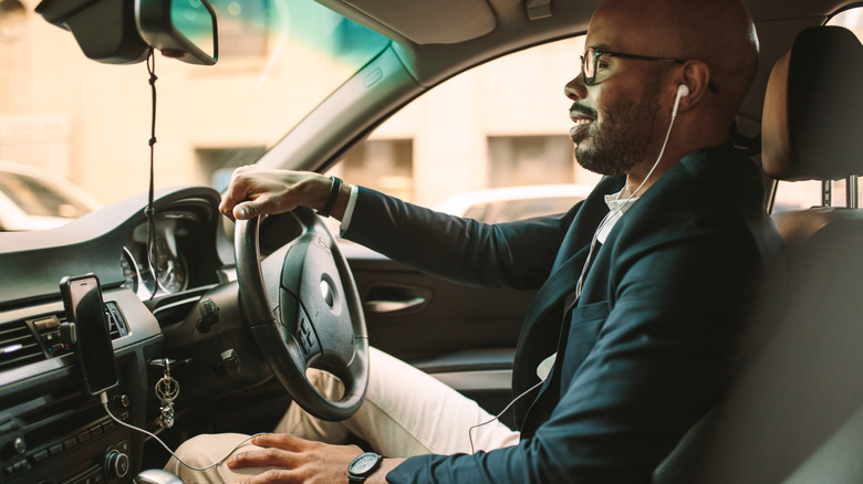 A person wearing earphones while driving a car